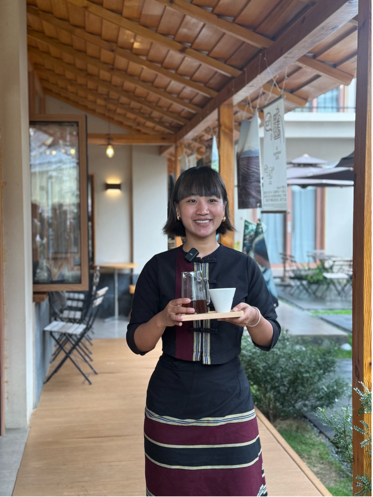 自身が経営するカフェでコーヒーを運ぶ趙華さん（撮影・虎遵会）。