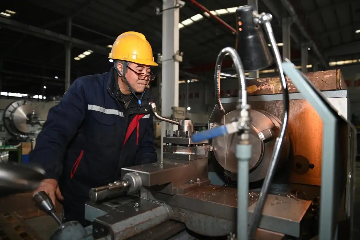 2025年1月7日、宝鶏市の永盛泰チタン業有限公司の機械加工工場で、高速コンプレッサー用チタン合金インペラー鍛造品を旋盤で加工する作業員（撮影・李一博）。