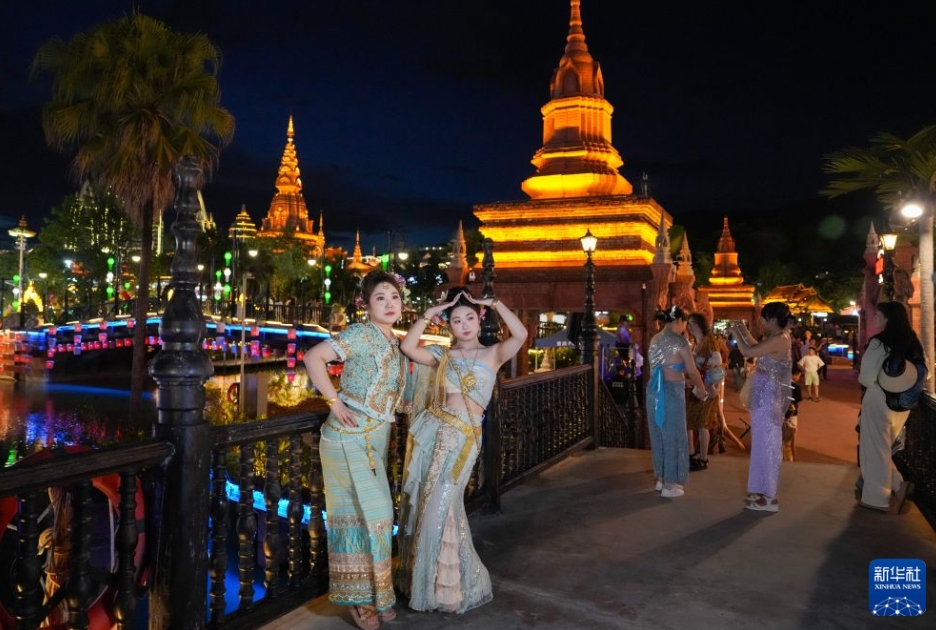 告荘西双景のナイトマーケット「星光夜市」で、民族衣装姿で記念写真を撮影する観光客（7月14日撮影・陳欣波）