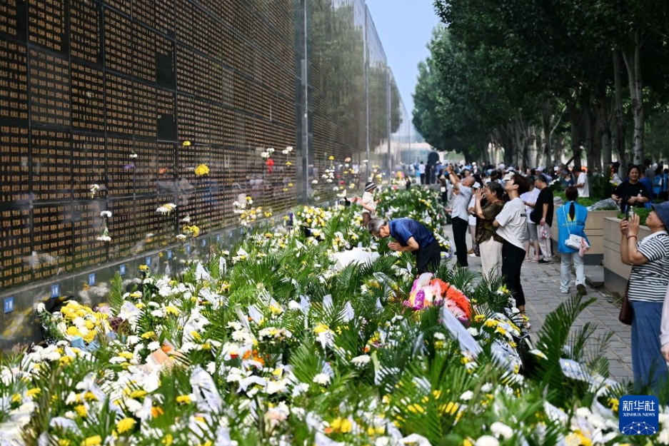 犠牲になった親族の名前が刻まれた石壁の前で頭を下げる男性（7月28日撮影・牟宇）。