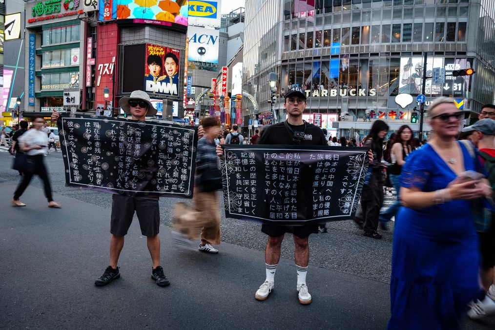東京の渋谷で、メッセージを掲げて、侵略の歴史を直視するよう日本の社会に対して訴えるフランス人のマルクス・デトレーズさんと鍾灝松さん（撮影・賈浩成）。