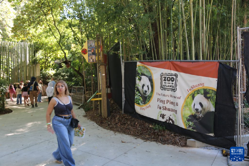 9月28日、米国のアトランタ動物園で、ジャイアントパンダをテーマにしたポスターの前を通り過ぎる来園者（撮影・劉亜南）。