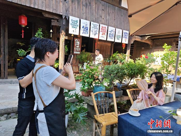 浙江省の後呉村で1軒目の「村カフェ」で写真を撮影する女性（撮影・林波）。