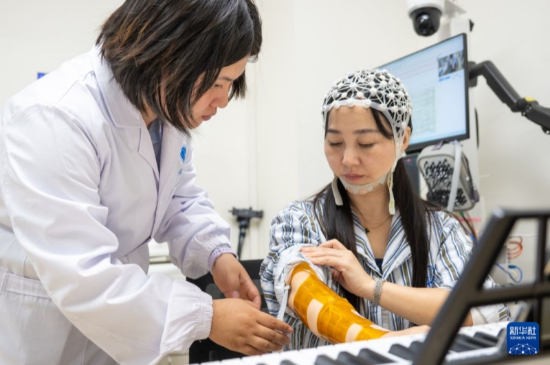 10月12日、患者の右前腕にマトリックス型機能的電気刺激電極を貼り付ける研究チームのスタッフ。撮影・伍志尊