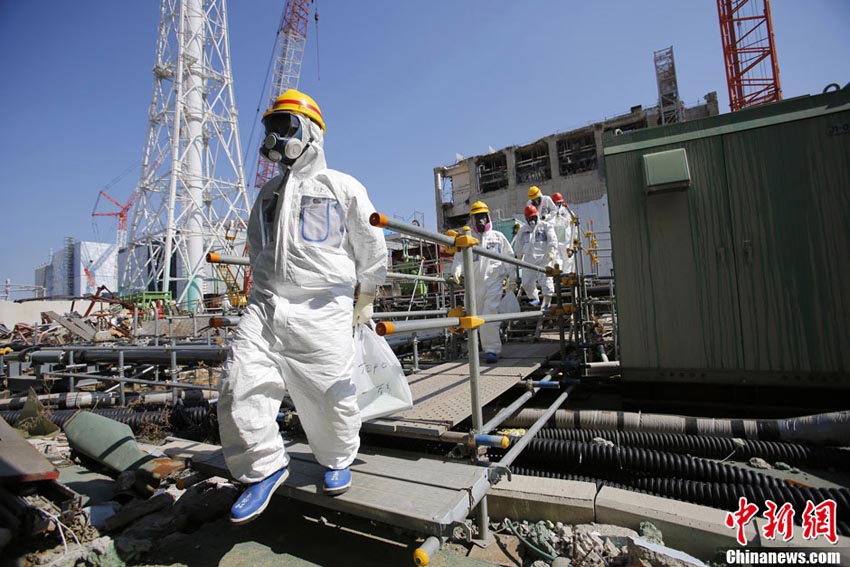 防護服を着用した東京電力職員が使用済み核燃料プールに記者らを案内する。