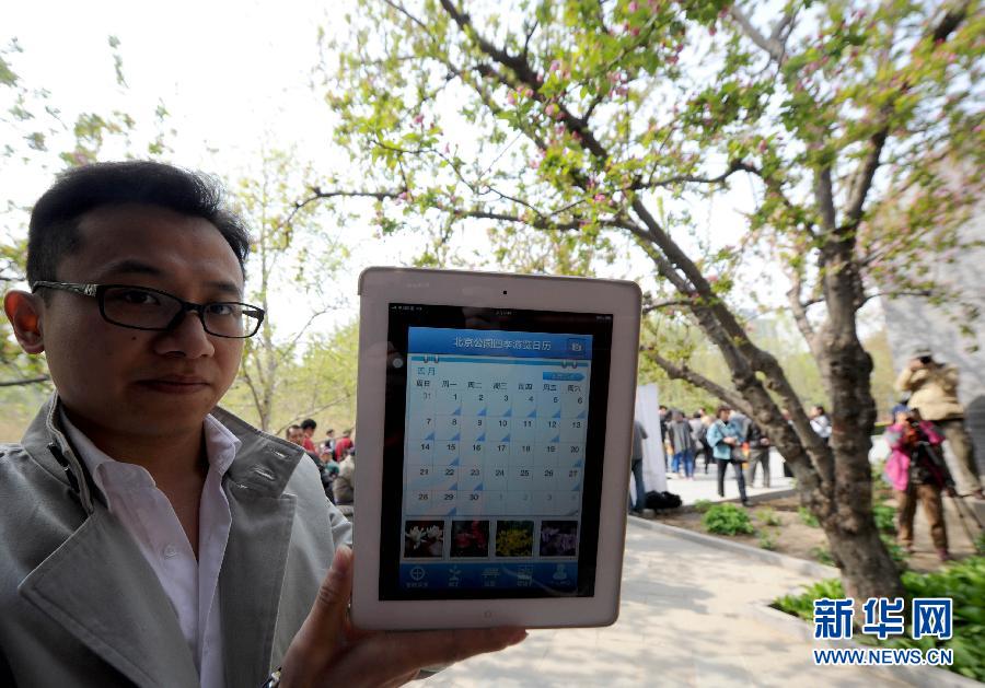 4月17日、北京元大都城垣遺跡公園で、タブレット機に表示された「北京の公園の四季見どころカレンダー」を見せる関係者。