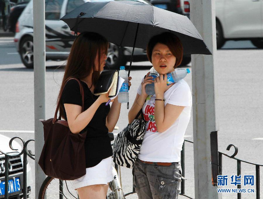 同日、上海の街角で氷水で気温を下げようとする通行人（右）。高気圧の影響を受けて同日、上海では気温が急上昇し、最高気温は36℃に達した。上海中心気象台は午前10時33分に上海では今年初となる高温の黄色警報を発表した。