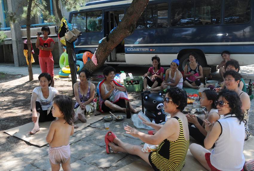 14日、朝鮮東部海域の海水浴場で、木の下で食事をしながらしゃべる観光客たち。