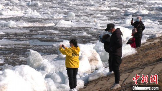 解氷の様子をカメラに収める観光客ら（撮影・王■、■は女へんに亭）。