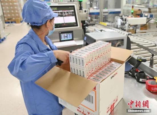 6月1日、北京市大興区にあるシノバックの工場で、新型コロナウイルスの不活化ワクチンパッケージラインで、箱を開けて登録のためのスキャンを行う作業員（撮影・侯宇）。