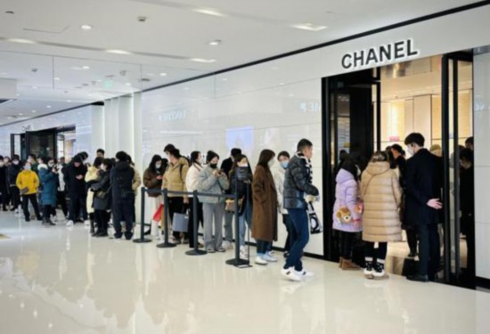 高級ファッションブランド・シャネルの店の前で新商品を買うために列を作る男女。