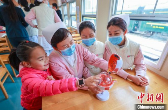 22日、「ライフライン・エクスプレス」で女の子に眼球の構造や目の健康づくりについて教える中国人民解放軍総病院(301病院)の医療従事者（撮影・賈天勇）。