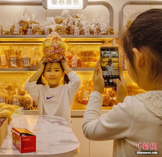 パン屋でパンを頭にのせて写真を撮る女の子。撮影・鄔高萍