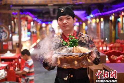 中国の伝統的な衣装を着て料理を運ぶホールスタッフ(撮影・陳超)。