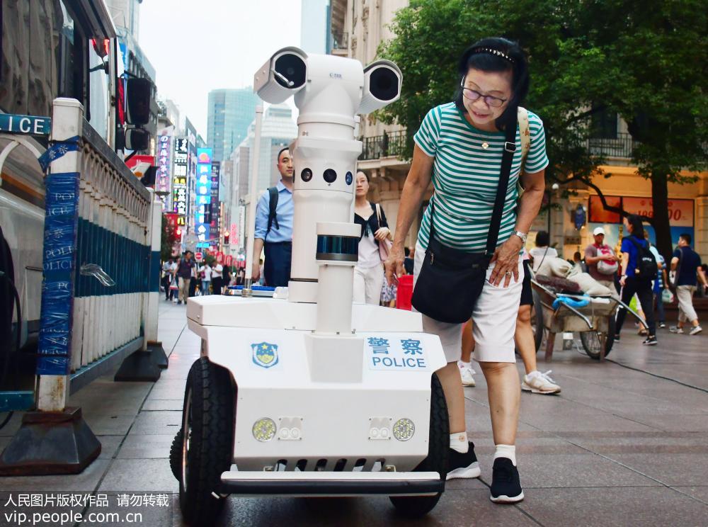 南京路をパトロールした初の警官ロボットに道行く人々も興味津々の様子。
