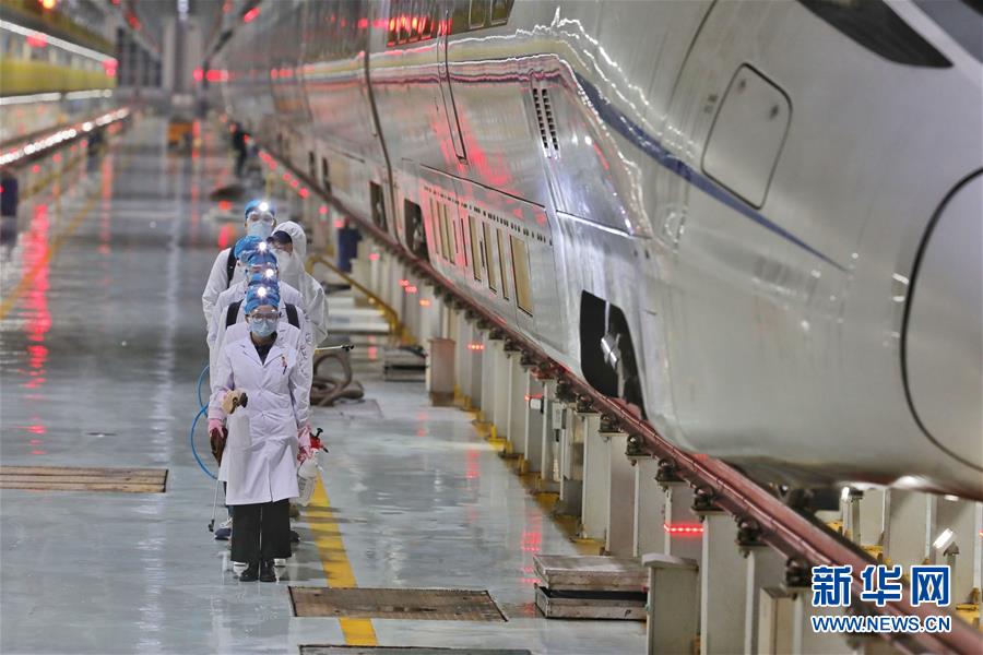 2月2日、高速列車の傍を通りながら消毒・防疫作業を行う作業員（撮影·欧東衢）。