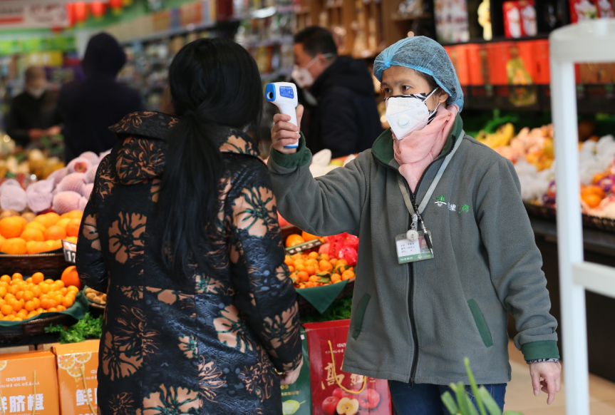 2020年1月31日、旧暦1月7日、漢口のあるスーパーで、新型コロナウイルス感染の拡大を予防するため、来店した買い物客の体温検査を行うスタッフ。この日スーパーには、野菜や果物などを買いに多くの市民が来店していた。