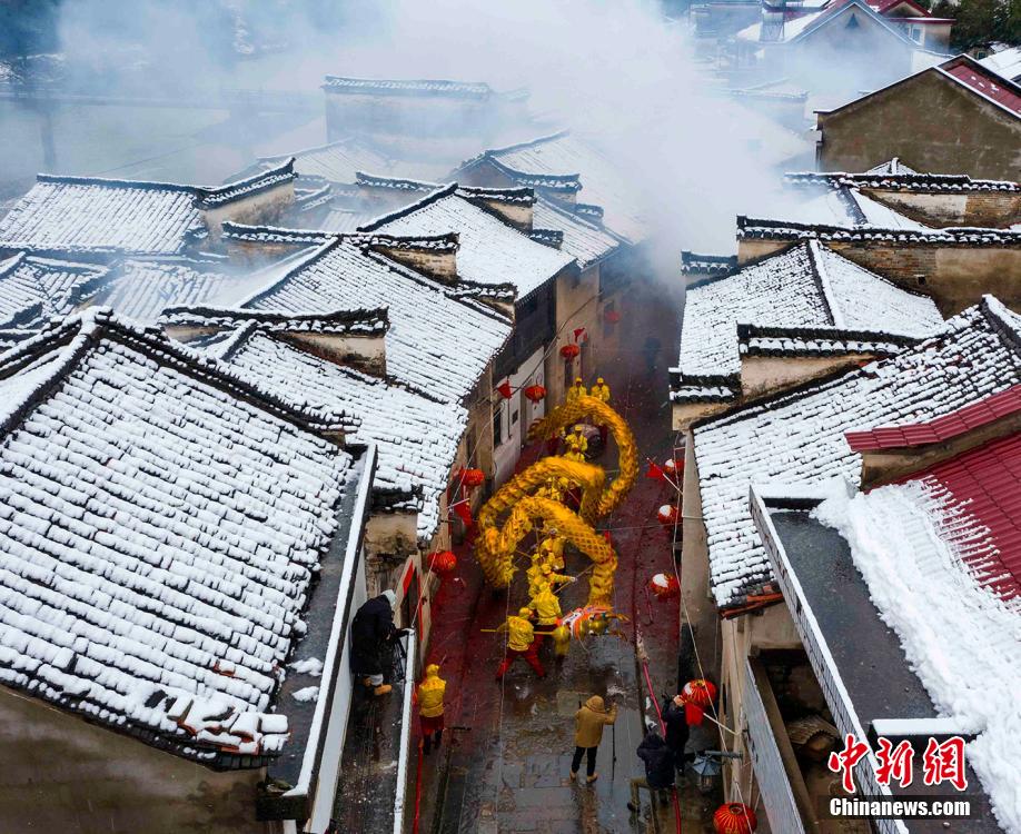 安徽省寧国市胡楽鎮で、雪が積もった歴史ある通りを胡楽司龍灯チームが元宵節の龍の舞いを披露しながらねり歩く様子（2月14日撮影・李暁紅）。