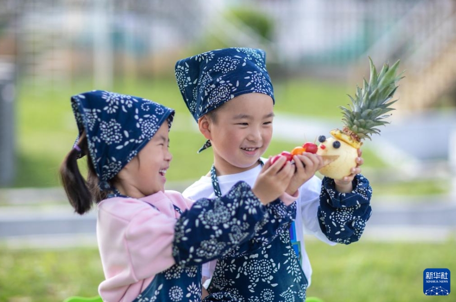 江蘇省興化市林湖郷にある中心幼稚園で、果物や野菜で作った「スマイル人形」で遊ぶ園児（5月8日撮影・周社根）。