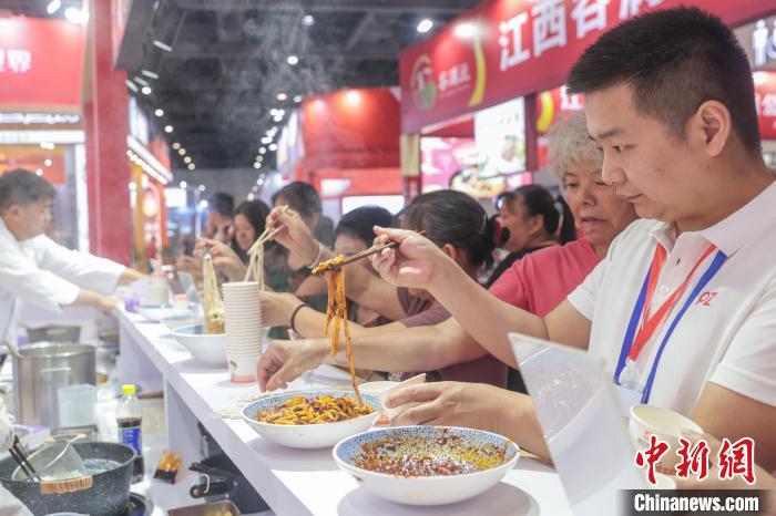 2025ライスヌードル産業交易会のある企業ブースでライスヌードルを食べる来場者。（6月13日撮影・劉力鑫）