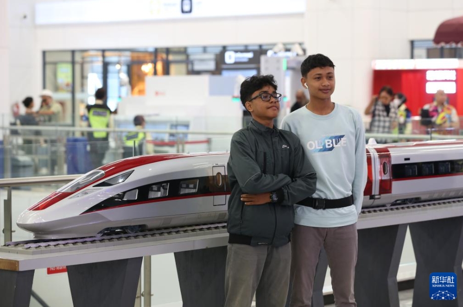 インドネシアの首都ジャカルタにあるジャカルタ・バンドン高速鉄道ハリム駅の待合ロビーで、高速鉄道の車両模型をバックに記念写真を撮影する2人の乗客（6月19日撮影・岑雲鵬）。