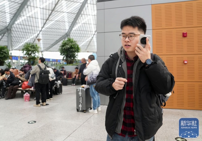 2月2日、上海南駅の待合ホールで、鉄道の「身軽に旅行」サービスの担当者からかかってきた電話に出る程燚さん。
