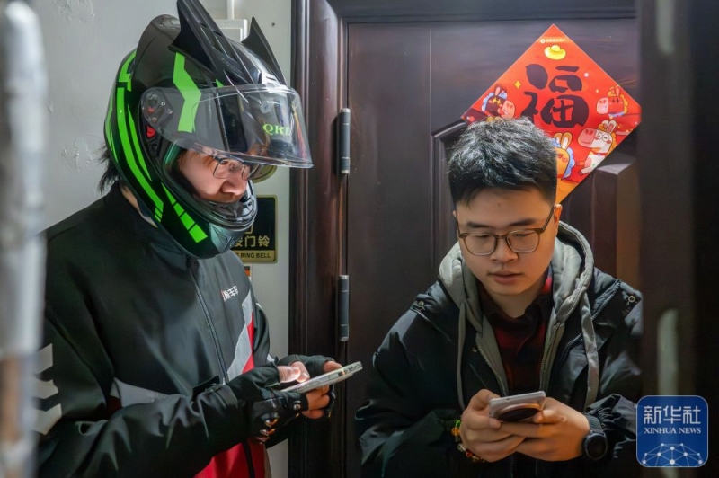 2月2日、湖北省武漢市の実家で、宅配業者のスタッフとスーツケースの情報を確認する程燚さん(写真右)。