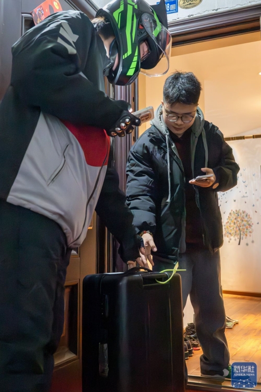 2月2日、湖北省武漢市の自宅で、スーツケースを受け取る程燚さん(写真右)。