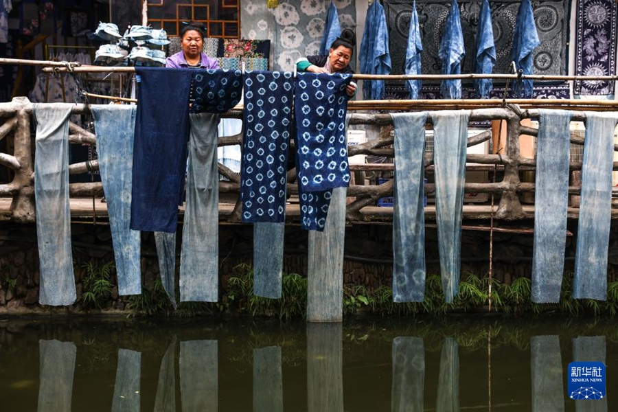 貴州省黎平県肇興トン寨で、藍染め作品を干すトン族女性の陸紅英さん（写真右）と村民（4月21日撮影・劉続）。