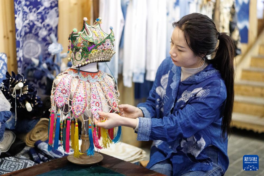 貴州省黎平県肇興トン寨で、刺繍作品を整えるトン族女性の陸雪梅さん（4月21日撮影・劉続）。