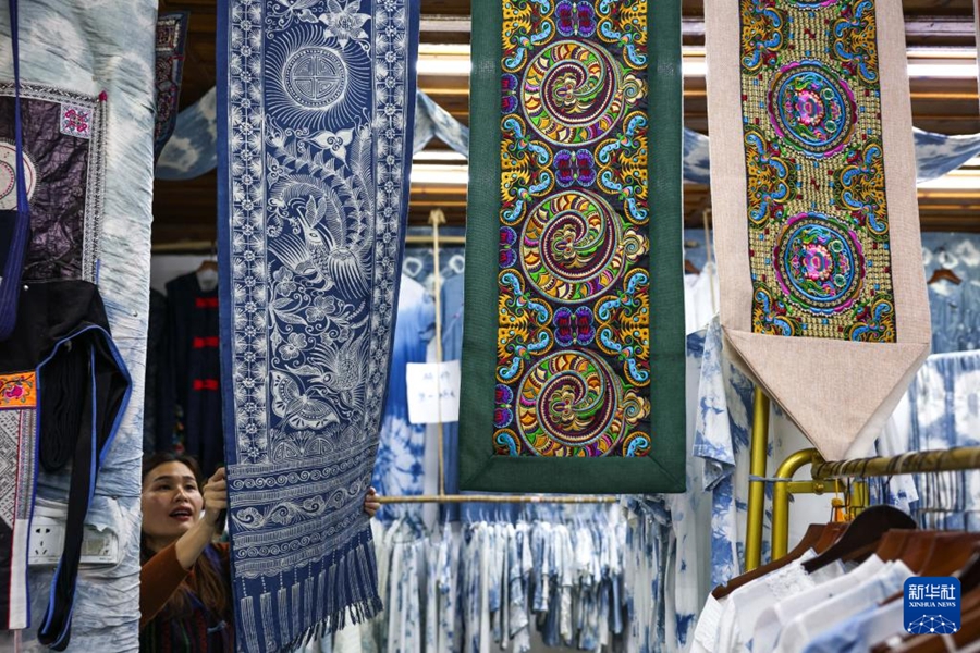 貴州省黎平県肇興トン寨で、ろうけつ染めや刺繍のテーブルランナーを掛けるトン族女性の陸雲妹さん（4月21日撮影・楊文斌）。