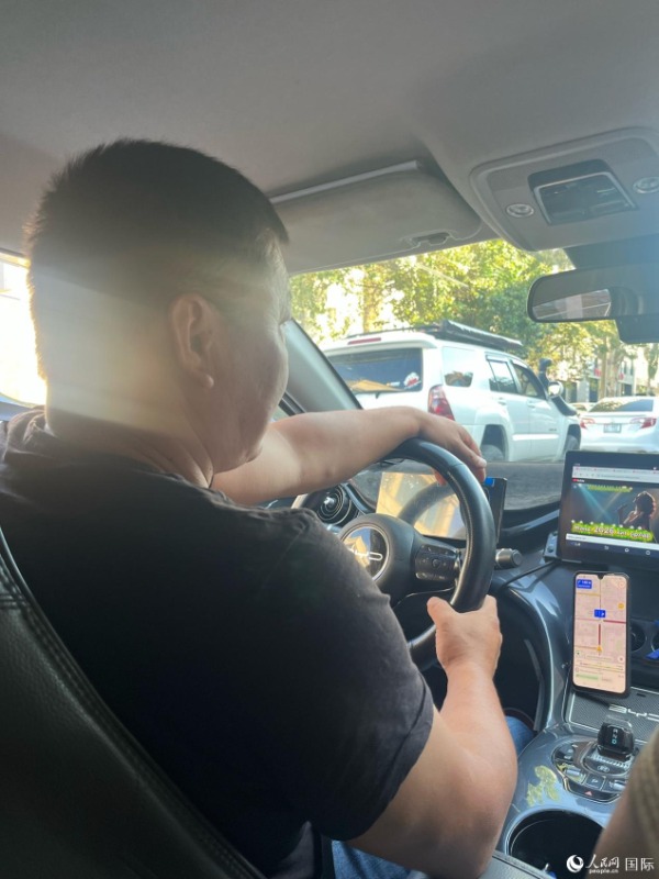 「中国の新エネ車は環境にやさしく、質も良く、価格も手ごろ。現地では中国製の製品が高く評価されており、中国製の電動自動車はハイエンド製品だ」と話す比亜迪(BYD)のタクシーを運転して2年になるタクシードライバーのアブラーソフさん(撮影・寇傑)。