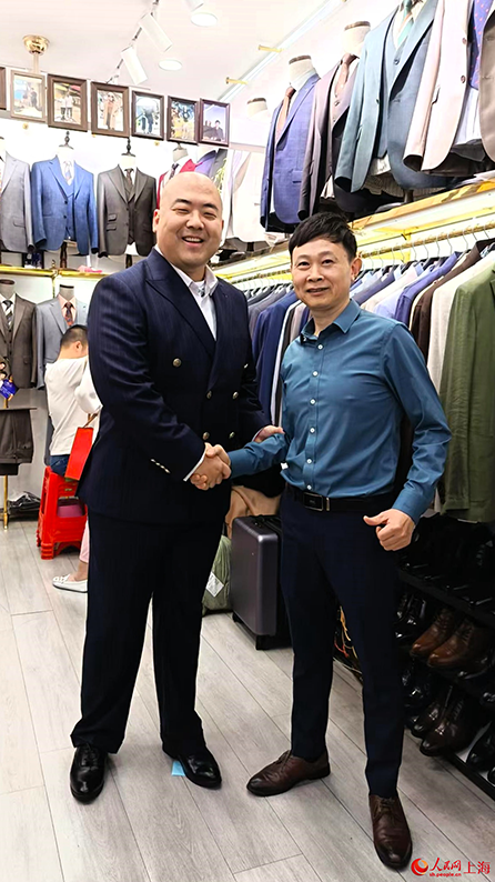 店主と記念写真を撮影する王俊生さん(写真左、写真提供・取材対象者)。