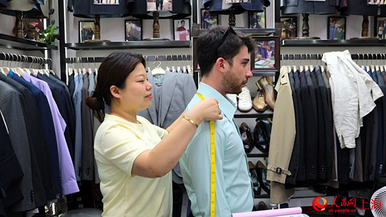 外国人男性の肩幅を測る店主の陳琴さん(撮影・楊雯)。